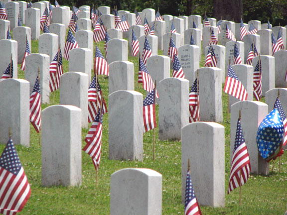 Picture of stark white tombstones and red, white and blue flags placed for the Memorial Day Holiday at the Tennessee Veterans Cemetery in Knoxville, TN